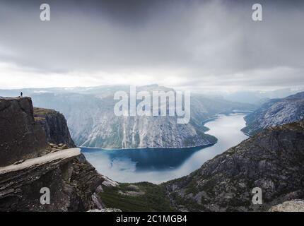 Blick auf Trolltunga Klippe und See zwischen Bergen, malerische Landschaft, Schönheit in der Natur, Paradies auf Erden, Sonnentag, Odda Stockfoto