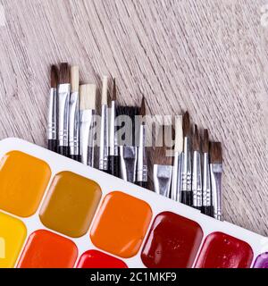 Papier, Aquarelle, Pinsel und einige Kunstgegenstände auf Holztisch Stockfoto