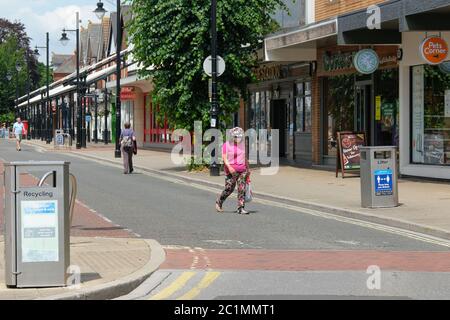 Eastleigh, Hampshire, Großbritannien. Juni 15. 2020 . Frau mit Maske und Hut durchquert ruhige Fußgängerstraßen, in denen Geschäfte, die soziale Distanzierungsrichtlinien als nicht-wesentliche Einzelhandelsgeschäfte anzeigen, zum ersten Mal seit dem 23. März 2020 wiedereröffnet werden. Britische Regierung Coronarirus Lockdown Eastleigh, Hampshire, UK Credit: Dawn Fletcher-Park/Alamy Live News Stockfoto