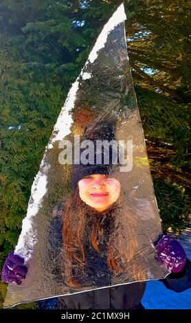 Mädchen versteckt hinter einem Stück Eisscholle in Choczewo, Pommern, Polen Stockfoto