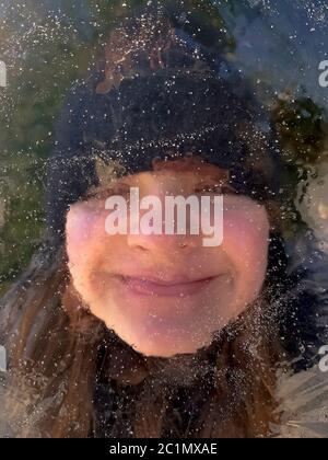 Mädchen versteckt hinter einem Stück Eisscholle in Choczewo, Pommern, Polen Stockfoto