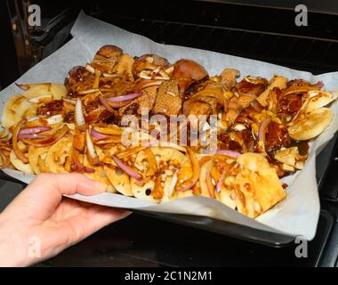 Rohes Hühnerfleisch mit Zwiebeln und Kartoffeln in einen Ofen geben Stockfoto