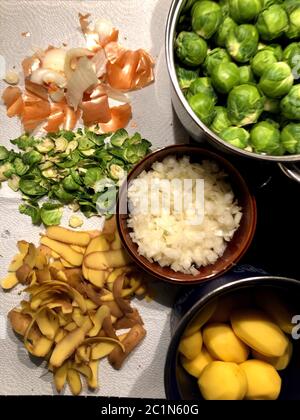 Gereinigter Rosenkohl, Brüsseler Rosenkohl, Zwiebel und Kartoffeln in einer Schüssel geschält und zusätzlich die Abfälle der Schalen Stockfoto