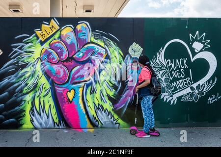 Brooklyn, Vereinigte Staaten Von Amerika . Juni 2020. Eine junge Frau schaut sich ihre Reflexion an, während sie am 15. Juni 2020 neben zwei Wandmalereien von Calicho Arevalo und Majo San in Brooklyn, New York, steht. Ihre Wandmalereien sind Teil einer Serie von Gemälden, die an drei Wänden der 4th Avenue zwischen Sackett und Union Street entstanden sind, um die Proteste zu unterstützen, die Rassengerechtigkeit fordern. (Foto von Gabriele Holtermann/Sipa USA) Quelle: SIPA USA/Alamy Live News Stockfoto