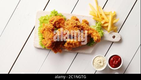 Saucen und Pommes frites in der Nähe von Kopfsalat und Chicken Wings Stockfoto