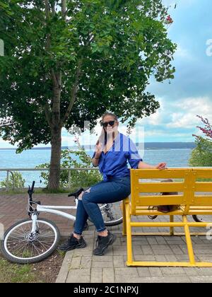 Foto eines Mädchens mit Fahrrad, das sich nach dem Sport auf einer Bank ausruht Stockfoto