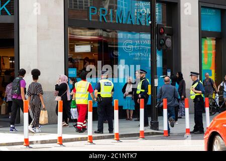 London, Großbritannien. Juni 2020. Polizisten beobachten Menschen, die vor dem Primark-Laden in der Londoner Oxford Street Schlange stehen, nachdem die Geschäfte wieder eröffnet werden durften. Kredit: SOPA Images Limited/Alamy Live Nachrichten Stockfoto