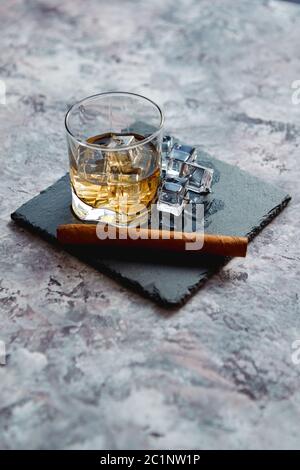 Glas Whisky mit Eiswürfel und Zigarre Stockfoto