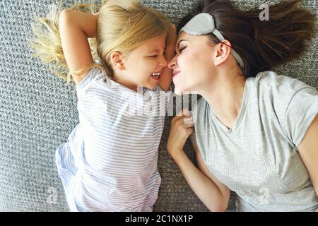 Nette liebende emotionale Frau umarmt ihre Tochter fest, während die Morgen im Bett und das Gefühl glücklich. Nase zu Nase Stockfoto