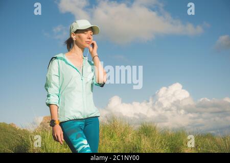 Fitness-Läufer Frau Musik auf der Natur hören. Portrait von schönen Mädchen tragen Kopfhörer Ohrhörer und Laufkappe. aga Stockfoto