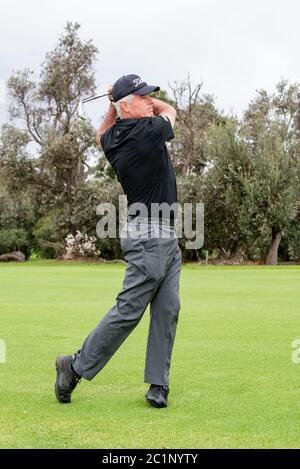 Mann spielt Golf und schaut nach unten Fairway, nachdem er gerade Ball getroffen hat Stockfoto