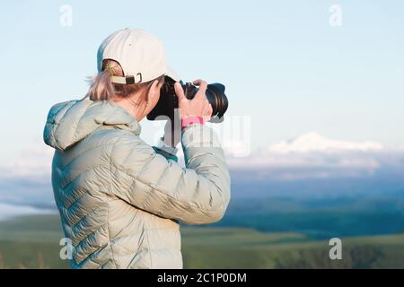 Porträt einer Fotografin in einer Mütze auf Natur fotografieren auf ihrer digitalen Spiegelkamera. Rückansicht Stockfoto