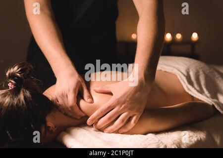 Nahaufnahme männliche manuelle Arbeiter tun Spa-Massage, um ein junges Mädchen in einem dunklen Raum Stockfoto