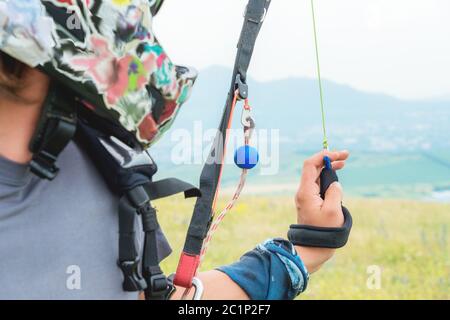 Nahaufnahme eines professionellen Gleitschirms, der Bremsen hält und wegschaut. Gleitschirmsportkonzept Stockfoto