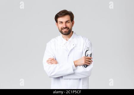 Krankenhaus, medizinisches Personal, covid-19 Behandlungskonzept. Professioneller Arzt in Scrubs Querarme lächelnd, hält Stethoskop, Patienten zu behandeln Stockfoto