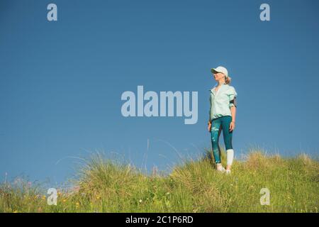 Fitness-Läufer Frau Musik auf der Natur hören. Portrait von schönen Mädchen tragen Kopfhörer Ohrhörer und Laufkappe. aga Stockfoto