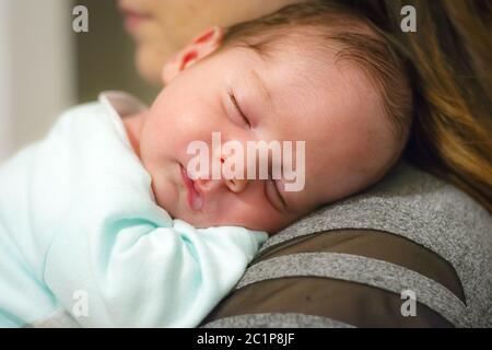 Baby schläft auf der Schulter seiner Mutter Stockfoto