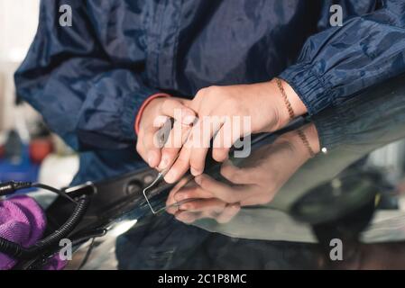 Nahaufnahme Auto Glasur Arbeiter Befestigung und Reparatur einer Windschutzscheibe oder Windschutzscheibe eines Autos an einer Garage Service-Station. Glas bohren Stockfoto