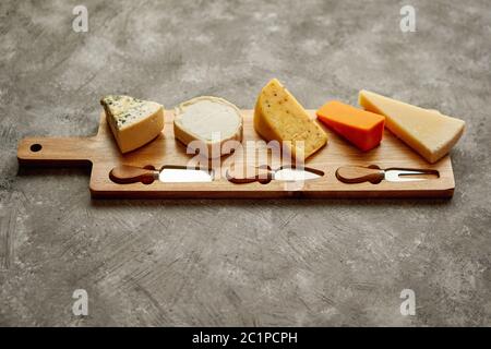 Sortiment von verschiedenen Arten von Käse auf Holzbrett mit Messer und Gabel serviert. Stockfoto