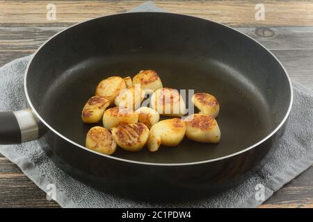 Jakobsmuscheln Meeresfrüchte mit Olivenöl in Antihaft-Pfanne auf Geschirrtuch auf dem Tisch sautiert Stockfoto