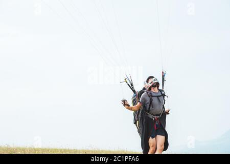 Nahaufnahme eines professionellen Gleitschirms, der Bremsen hält und wegschaut. Gleitschirmsportkonzept Stockfoto