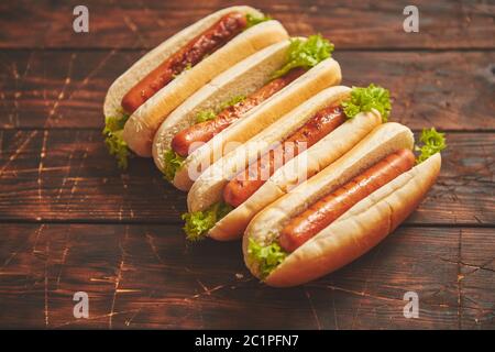 Leckere amerikanische Hot Dogs sortiert in Reihe. Auf Holztisch platziert Stockfoto