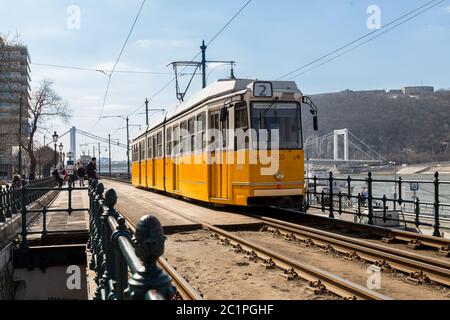 Budapest, Ungarn, März 22 2018: Gelbe Straßenbahn im frühen Winter mit bewölktem Himmel. Die Straßenbahn Nr. 2 ist berühmt für ihre beste fahrt in europa Stockfoto