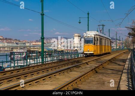 Budapest, Ungarn, März 22 2018: Gelbe Straßenbahn im frühen Winter mit bewölktem Himmel. Die Straßenbahn Nr. 2 ist berühmt für ihre beste fahrt in europa Stockfoto