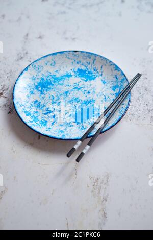 Blaue Hand bemalte Keramik Servierteller mit Stäbchen auf der Seite Stockfoto