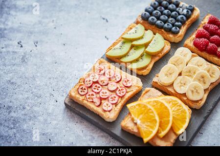 Vollkornbrot Schichten mit Erdnussbutter und verschiedene Früchte Stockfoto