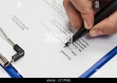 Eine nicht erkennbare Person, die eine unverbindliche Absichtserklärung ausfüllt. Nahaufnahme Stockfoto