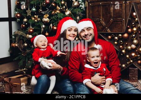 Glückliche Familie mit zwei entzückende Kinder, die Spaß am Weihnachtsbaum. Stockfoto