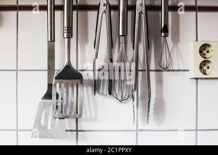 Die Küchenutensilien hängen an der Wand in der Küche Stockfoto