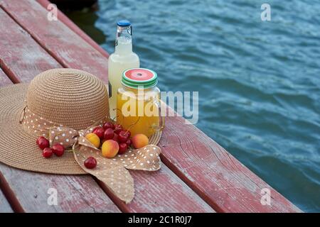 Ein Glas tropischer exotischer Multifruitsaft und Früchte am Pier. Tropisches Picknick am Strand Stockfoto