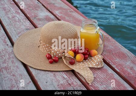 Ein Glas tropischer exotischer Multifruitsaft und Früchte am Pier. Tropisches Picknick am Strand Stockfoto