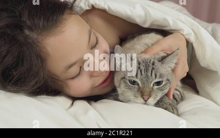 Gerne jugendlich Mädchen küsse und Gespräche mit Thai Katze im Bett Stockfoto