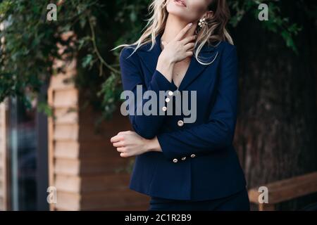 Elegante blonde Dame im dunkelblauen Anzug mit goldfarbenen Knöpfen. Stockfoto