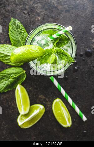 Cocktail mit Limette, Minze und Eiswürfeln auf schwarzem Tisch. Draufsicht. Stockfoto