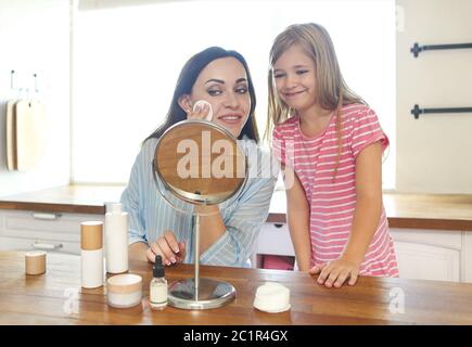 Nette lächelnde Mutter und Tochter Anwendung Gesichtscreme Stockfoto