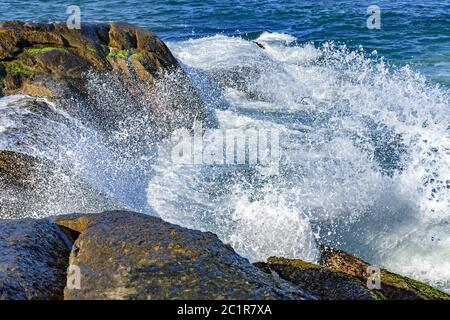 Wellen krachen über Felsen mit Wassertropfen Stockfoto