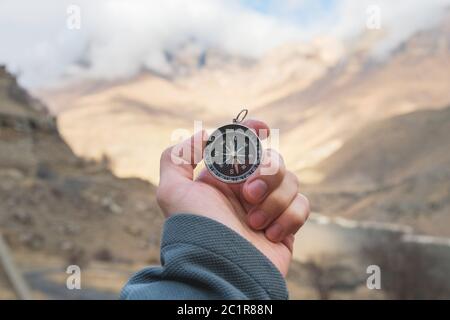 Ein männlicher Wanderer sucht im Herbst eine Richtung mit einem magnetischen Kompass in den Bergen. Blickpunkt. Mann's Hand Witz Stockfoto