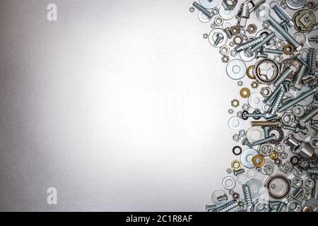Verschiedene Größen von Schrauben, Schrauben und Muttern für Hausreparaturen auf metallisch grauem Hintergrund Stockfoto
