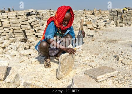 Lokaler Mann schneidet Salzblöcke in einem Salzbruch am Assale Salt Lake, Hamedala, Danakil Depression, Afar Region, Äthiopien Stockfoto