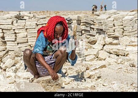 Lokaler Mann schneidet Salzblöcke in einem Salzbruch am Assale Salt Lake, Hamedala, Danakil Depression, Afar Region, Äthiopien Stockfoto