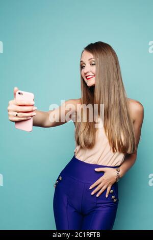 Pretty Woman nimmt selfie per Handy über grünen Hintergrund. Stockfoto