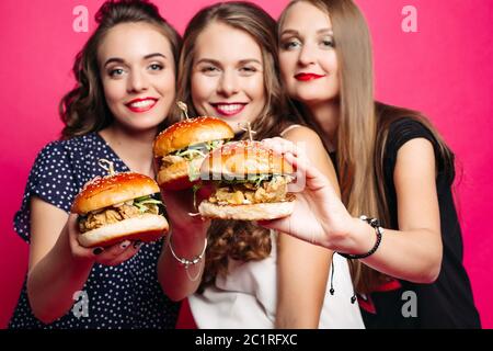 Hübsche Freundinnen mit saftigen Hamburger. Stockfoto