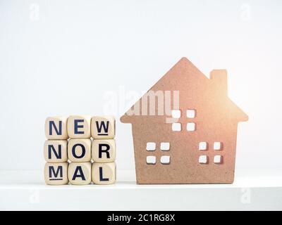 New normal und sicher bleiben zu Hause Konzept, Holzhaus und Worte auf Holz Alphabet Würfel auf weißem Hintergrund. Stockfoto