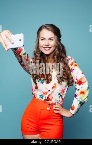 Positive Mädchen lächeln und tacking Selbstporträt auf dem Smartphone. Stockfoto