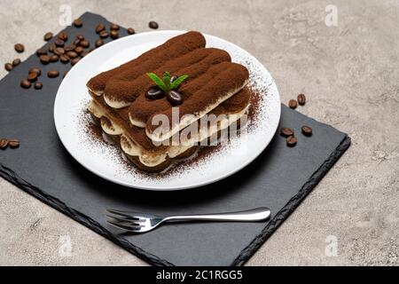 Klassisches Tiramisu Dessert auf Keramikplatte auf Betongrund Stockfoto