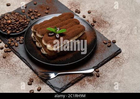 Klassisches Tiramisu Dessert auf Keramikplatte auf Betongrund Stockfoto